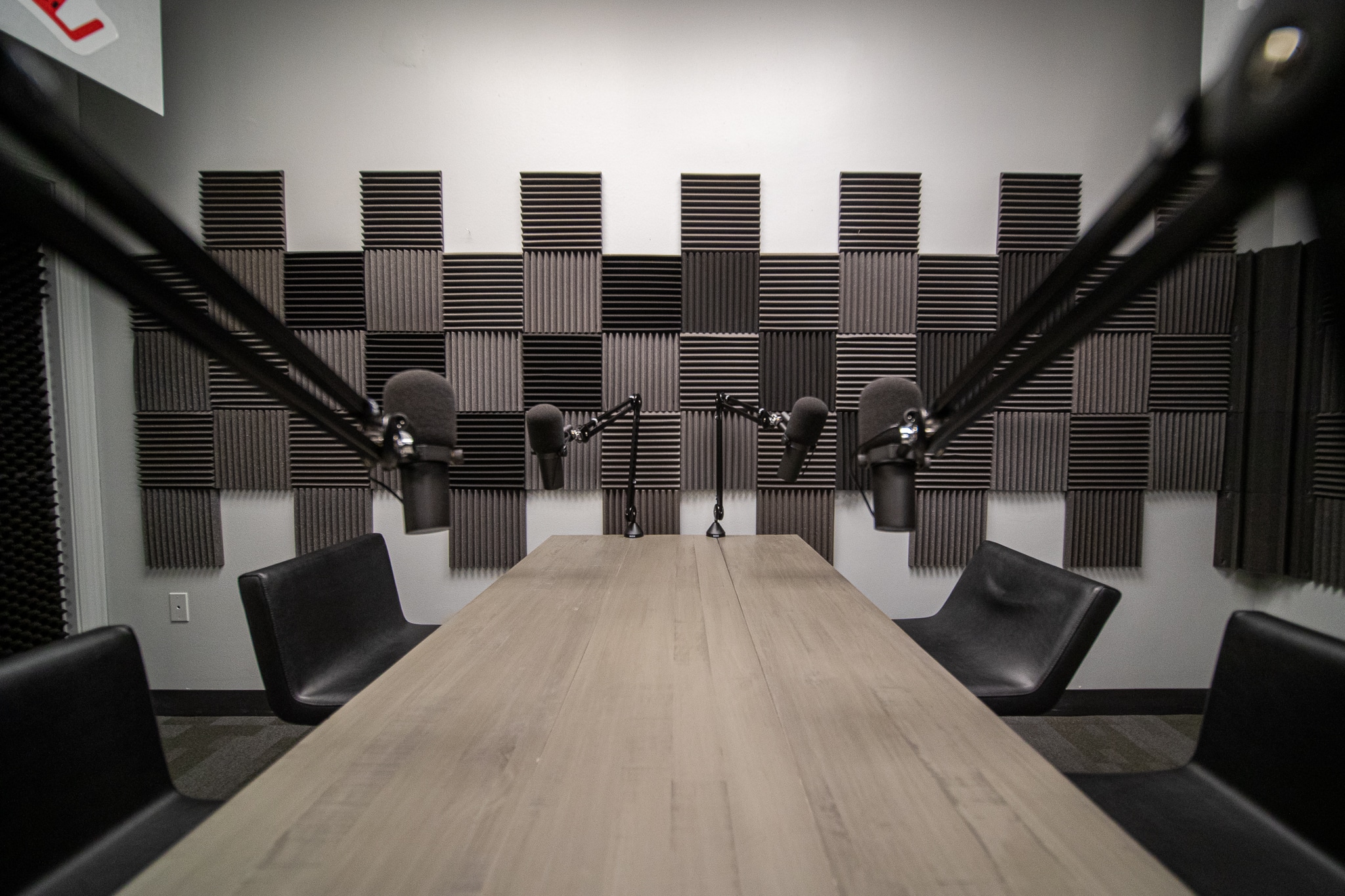 The table and four chairs inside a podcast recording studio.