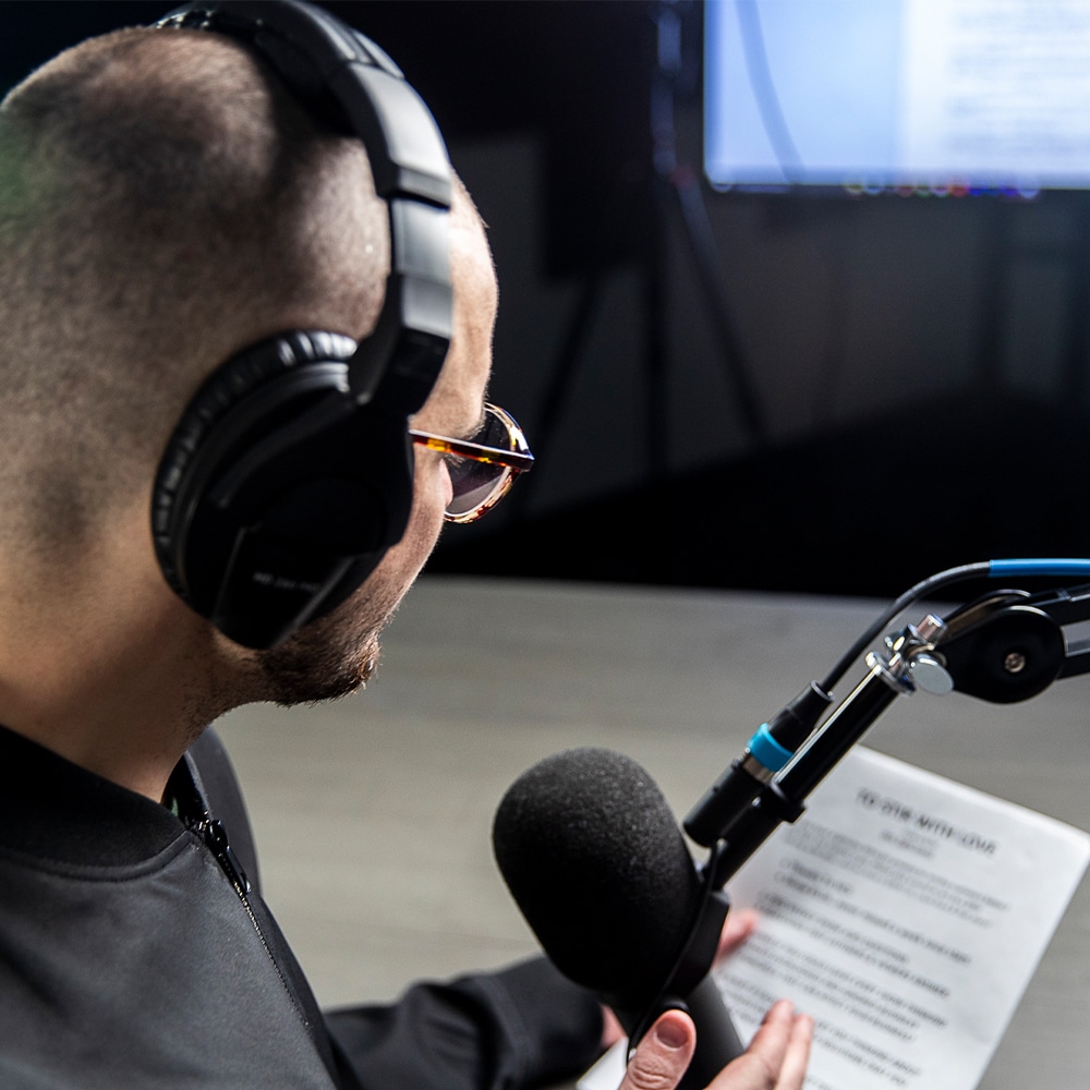 A man recording a voice over into a microphone.